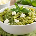 pasta pesto feta in white bowl with basil and cheese