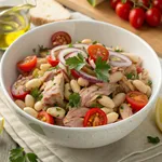 Tuna and white bean salad in a bowl with cherry tomatoes and lemon wedges