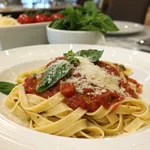 Plated spaghetti alla chitarra with tomato sauce and fresh basil on white plate