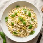 Creamy lemon ricotta pasta topped with fresh basil and grated parmesan in a white bowl