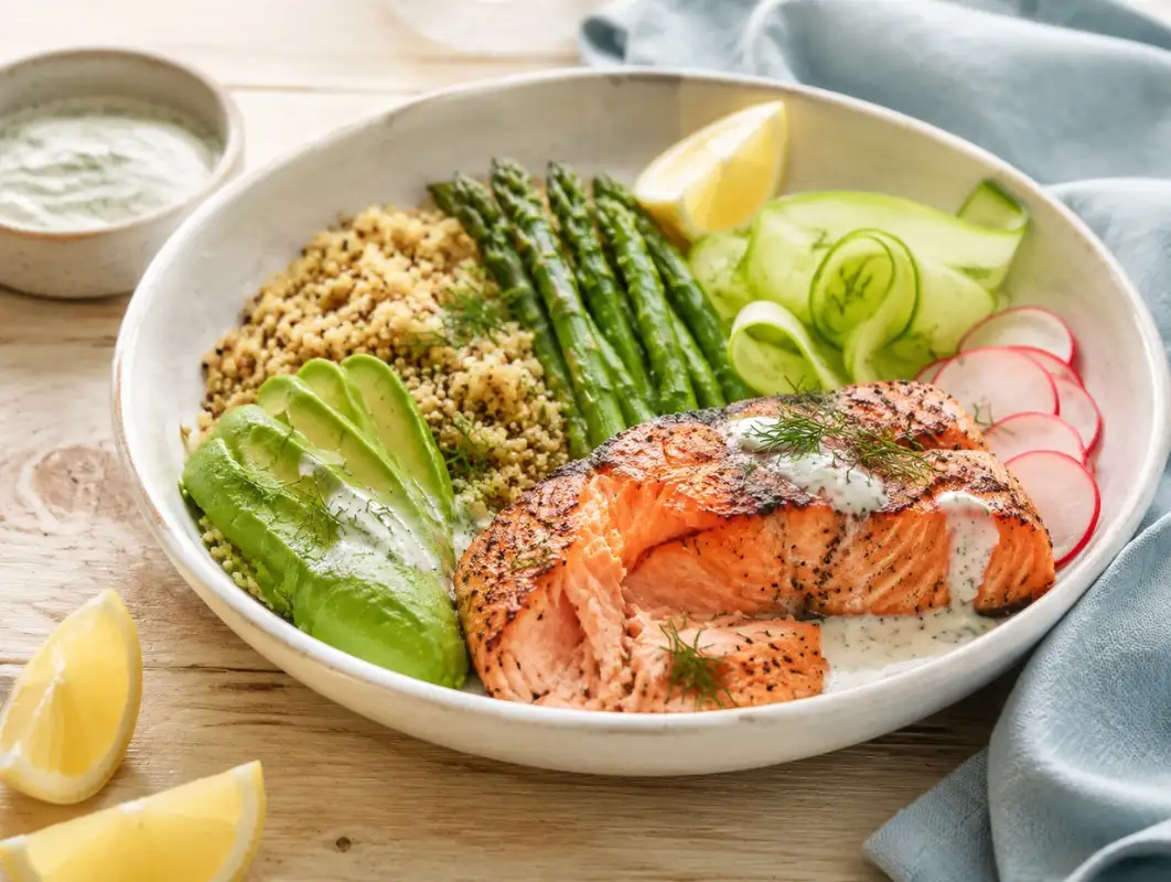 Spring Salmon and Avocado Mediterranean Bowl (35 Min) 1 Three-quarter view of spring salmon and avocado bowl with quinoa, asparagus, radish and lemon dill yogurt drizzle